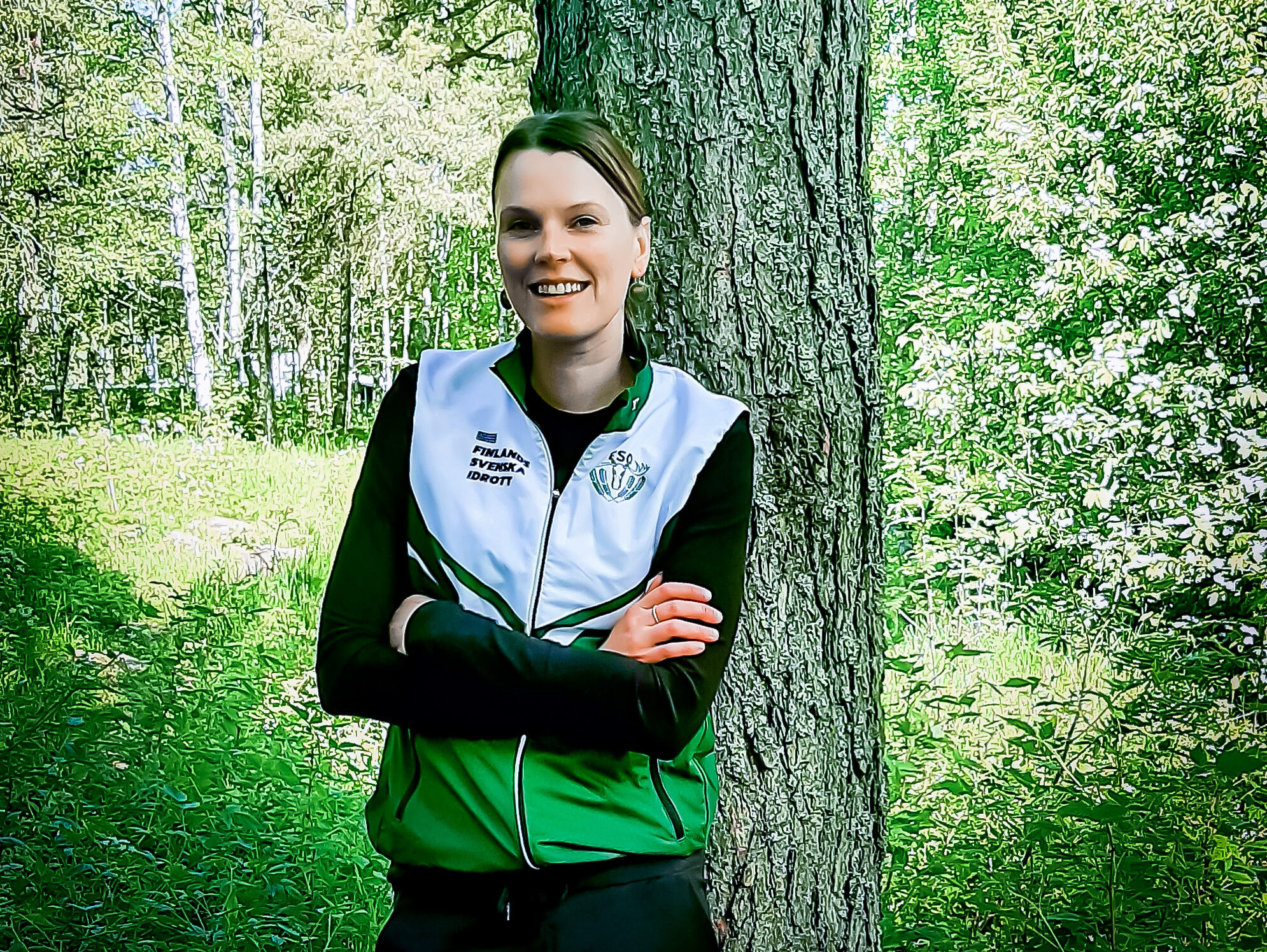 En porträttbild på Saara Norrgrann när hon står utomhus mot ett träd i en träningsuniform.